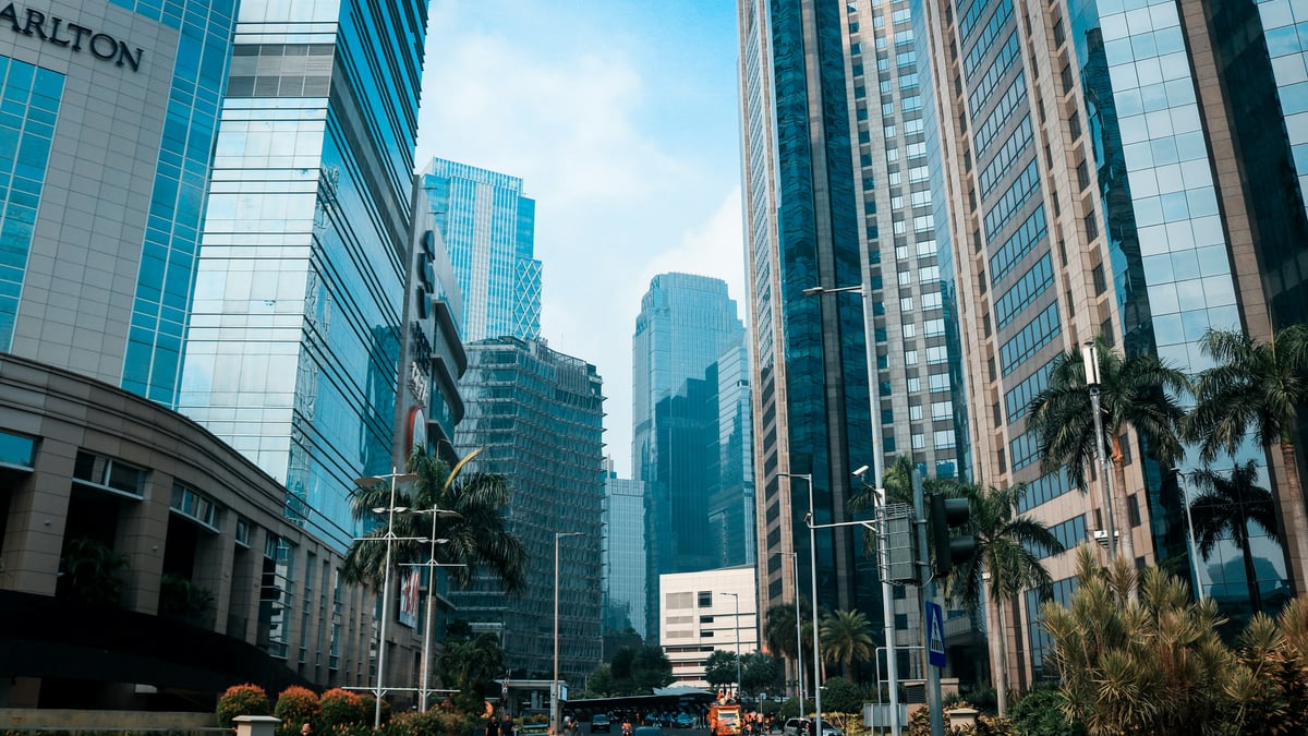 Gedung perkantoran kaca di kawasan bisnis Jakarta pada siang hari dengan langit biru
